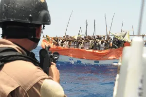 Piracy Prints: U.S. Sailor trains his gun on over twenty suspected pirates in a ramshackle boat the Gulf of Aden