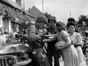 Candid Group Portraits Prints: Three U.S. soldiers eat on homemade food on plates prepared by a French woman in Summer 1944