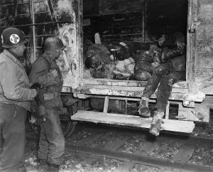 Liberation Prints: Two U.S. soldiers looking at dead prisoners on railroad car at an unidentified concentration camp