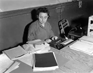 Womens Army Corps Prints: U.S. WAC Private First Class typing at a rough plywood desk in Normandy