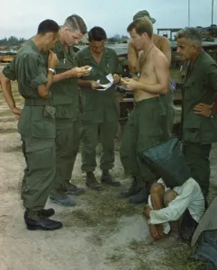 Republic Of Vietnam Prints: Vietnam War. A suspected Viet Cong sits on the ground with a black bag over his head while several US soldiers examine