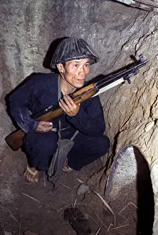 Bunker Prints: Vietnam War, a Viet Cong, soldier crouches in a bunker with an SKS rifle, circa late 1960s