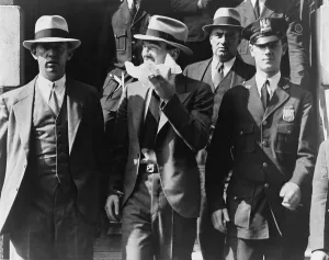 Courts Prints: Vincent Coll (center with handkerchief) leaving homicide court surrounded by police officers