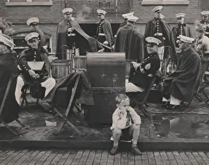 Brick Prints: Watching for the parade, child seated on a curb with a military band behind