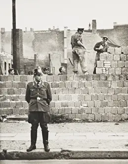 Communism Prints: West Berlin policeman stands before the concrete block wall dividing East and West Berlin