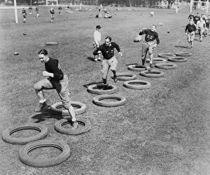 Players Prints: West Point's football squad high stepping through a maze of tires during their first practice