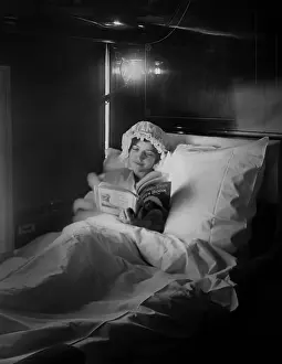 Railroad Prints: Woman reads in an electric-lighted berth on a deluxe overland express train, c. 1915-1919