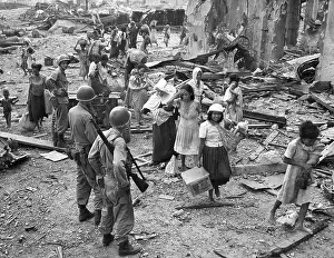 Suffering Prints: Women and children picking their way barefooted over the wreckage of North Manila