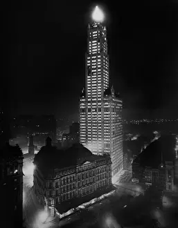 Gilbert Prints: Woolworth Building towers over the City Hall Post Office and Courthouse at night