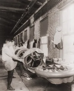 Rubber Prints: Workers in a tire shop applying the first ply of rubber on a handmade tires. 1916