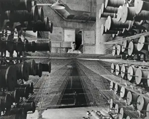 Complexity Prints: Workman operating an industrial loom strung with hundreds of wool threads