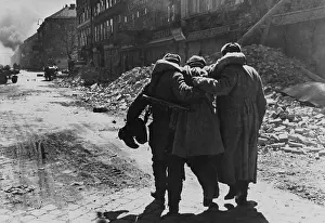 Austria Prints: Wounded Soviet (Russian) soldier helped by two comrades in a street filled with rubble