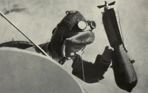 Aviator Prints: WW1 pilot dropping a handheld bombing from his plane. 1914-1918. (BSLOC_2012_4_71)