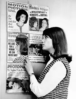 A young women observes a display of celebrity gossip magazine covers featuring widowed First Lady Jacqueline Kennedy and the often married actress Elizabeth Taylor. Mar. 28, 1965